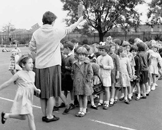 Children lined up, ready to go into the school to begin their day, circa 1957