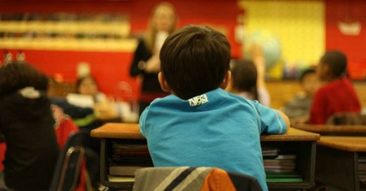 A young boy, enrolled in a private-school, looking towards the front of the class